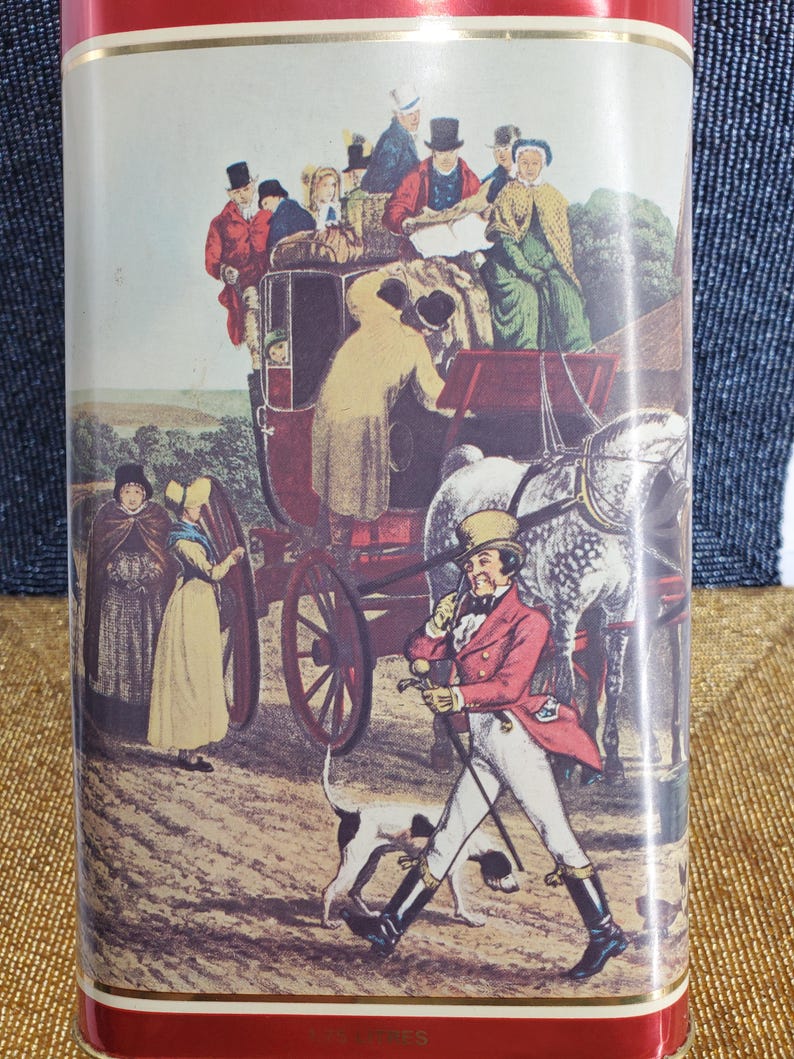 May include: A rectangular tin with a red border displays a vintage illustration of a horse-drawn carriage with passengers and people in period clothing. A man in a red coat walks with a dog.