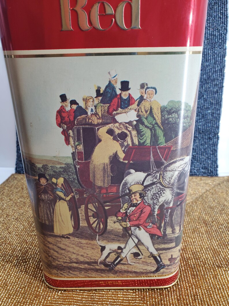 May include: Red metal umbrella stand featuring a vintage illustration of a horse-drawn carriage and people in period clothing. The word "Red" is displayed in gold lettering at the top.