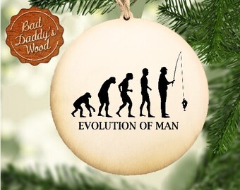 Op de afbeelding: Een ronde houten ornament met een witte achtergrond en zwarte silhouetten van de stadia van de menselijke evolutie, eindigend met een man die een hengel vasthoudt. De tekst "EVOLUTION OF MAN" is onder de silhouetten gedrukt.