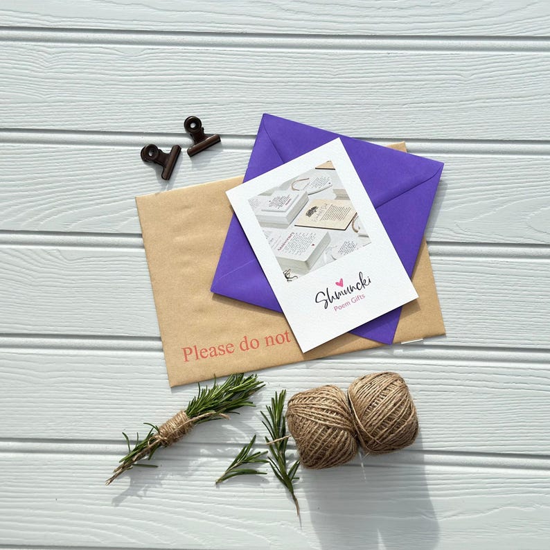 May include: An overhead shot shows a collection of stationery items. A white card with the text "Shmuncki Poem Gifts" is layered over a purple envelope and a brown envelope with the text "Please do not". Twine, rosemary, and two small clips complete the arrangement.