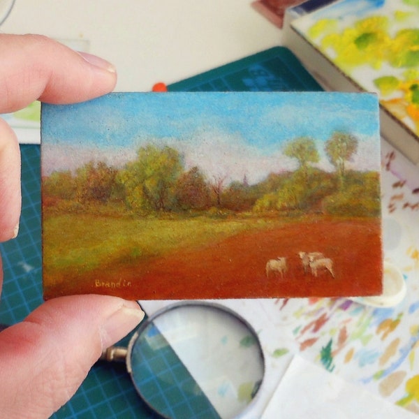 Peinture miniature d'un paysage de campagne avec prairie, clocher et moutons