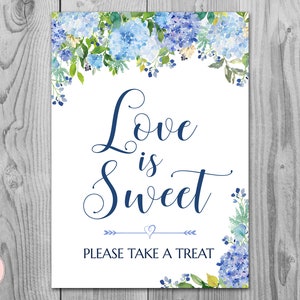 May include: A white sign with blue floral borders and the text "Love is Sweet" in navy blue script. The sign also says "Please take a treat" in navy blue text.