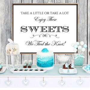 May include: A wedding dessert table with a sign that reads "Take a little or take a lot. Enjoy these sweets. We tied the knot!" The table is decorated with blue and white candy, cupcakes, cake pops, and a blue and white cake.