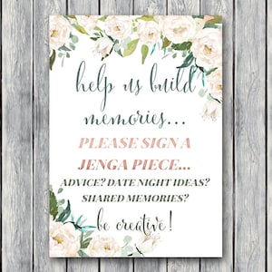May include: White floral printable sign with the text "help us build memories... PLEASE SIGN A JENGA PIECE... ADVICE? DATE NIGHT IDEAS? SHARED MEMORIES? be creative!"