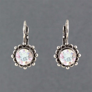 May include: A pair of silver earrings with a round, iridescent crystal in the center of each earring. The crystal is surrounded by a silver filigree design.