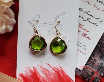 Puede incluir: Un par de pendientes de piedra preciosa verde con engastes de oro. Los pendientes tienen forma de lágrima y cuelgan de un gancho de oro.