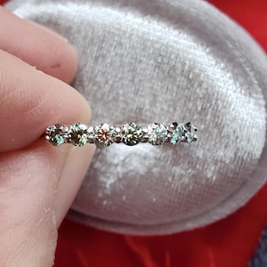 May include: A silver band ring with a row of green gemstones.
