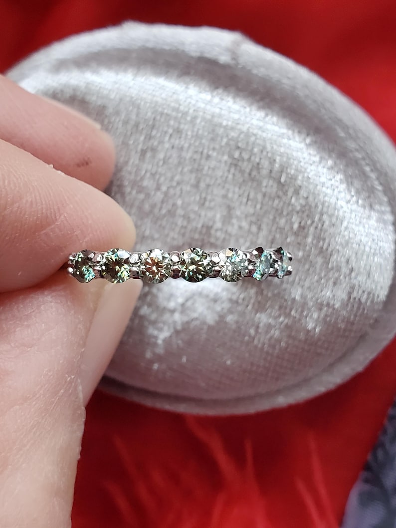 May include: A silver band ring with a row of green gemstones.