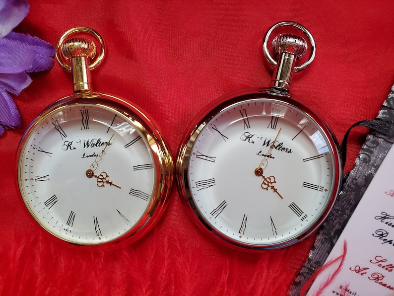 May include: Two pocket watches with white faces, Roman numerals, and ornate hands. One watch has a gold-tone case and the other a silver-tone case. The watches are marked "R. Walters London".