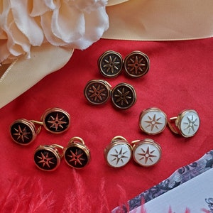 May include: A set of eight gold cufflinks with a star design. The cufflinks have a black, white, or brown enamel finish.