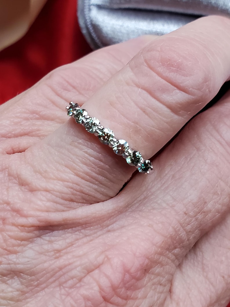 May include: A silver band ring with a row of small, clear, round gemstones.