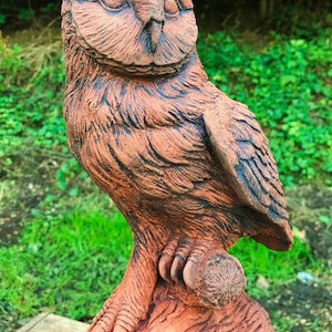 Op de afbeelding: Een terracotta uilenbeeld dat op een boomstronk zit. De uil heeft gedetailleerde veren en een realistische uitdrukking. Het beeld is van een rustieke bruine kleur.