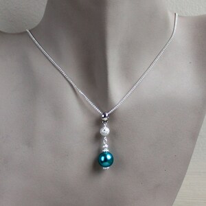 May include: A silver chain necklace with a teal pearl pendant and two silver beads.