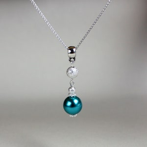 May include: A silver chain necklace with a teal blue pearl and two silver beads.