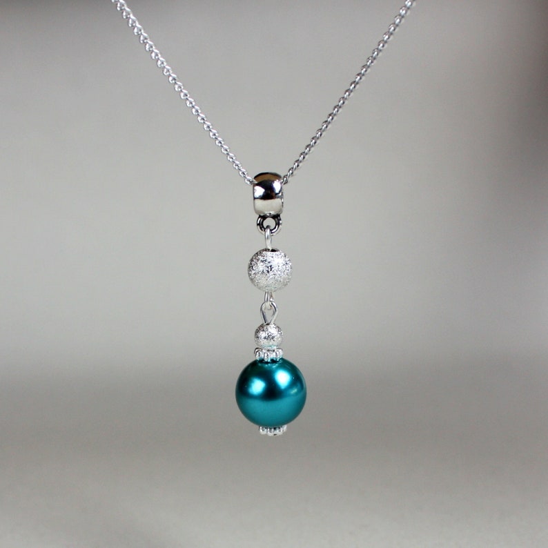 May include: A silver chain necklace with a teal blue pearl and two silver beads.