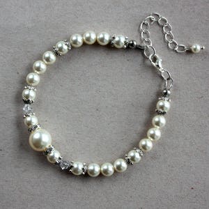 May include: A white pearl bracelet with a silver clasp and extender chain. The bracelet features small silver accents between each pearl.