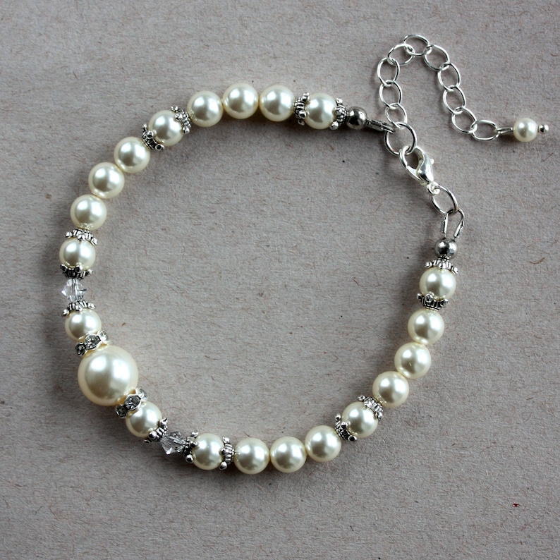 May include: A white pearl bracelet with a silver clasp and extender chain. The bracelet features small silver accents between each pearl.