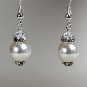 Peut inclure: Une paire de boucles d'oreilles en argent avec des perles blanches et des accents de cristal.