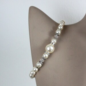 May include: A white pearl bracelet with silver accents and clear crystal beads. The bracelet is on a white mannequin.