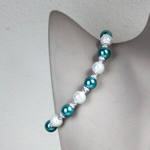 May include: A teal and silver beaded bracelet with alternating round beads. The silver beads have a textured surface.