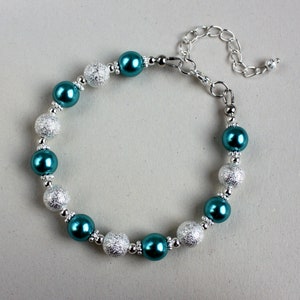 May include: Teal and silver beaded bracelet with a silver clasp.