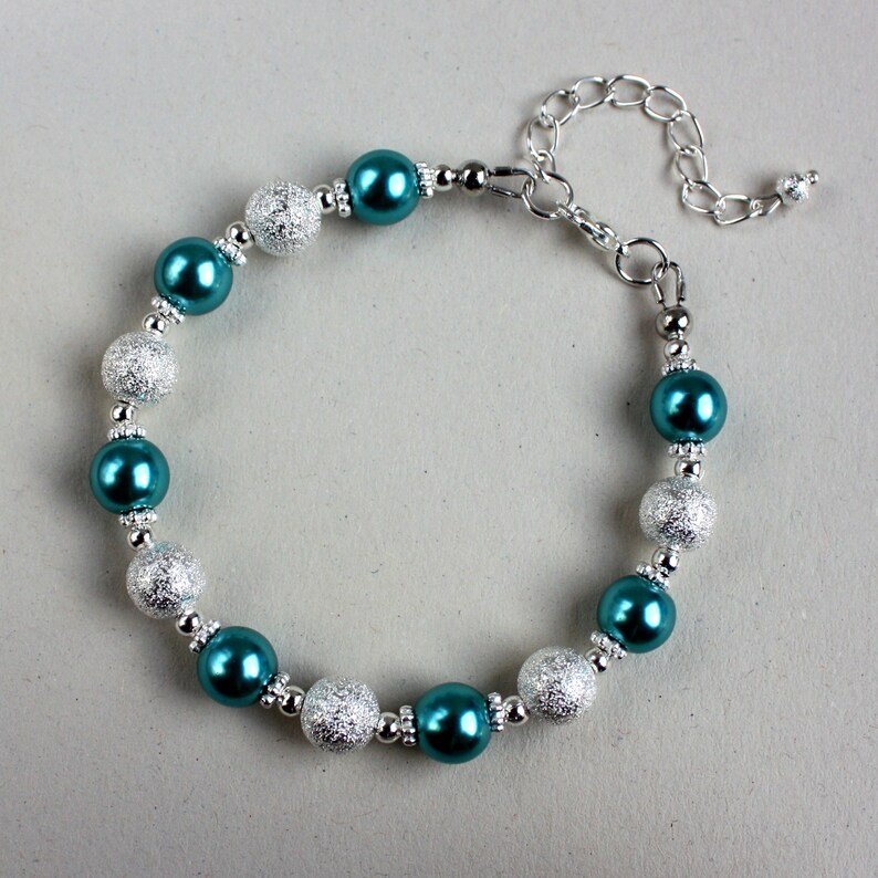 May include: Teal and silver beaded bracelet with a silver clasp.