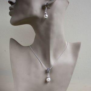 Peut inclure: Un collier et des boucles d'oreilles en argent avec un pendentif en perle blanche et des boucles d'oreilles assorties. Le collier a une cha&icirc;ne d&eacute;licate et un pendentif simple avec un motif floral.