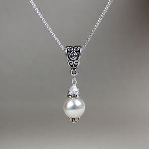 Peut inclure: Un collier en cha&icirc;ne argent avec un pendentif argent&eacute; orn&eacute; d'une perle blanche et d'accents en cristal.
