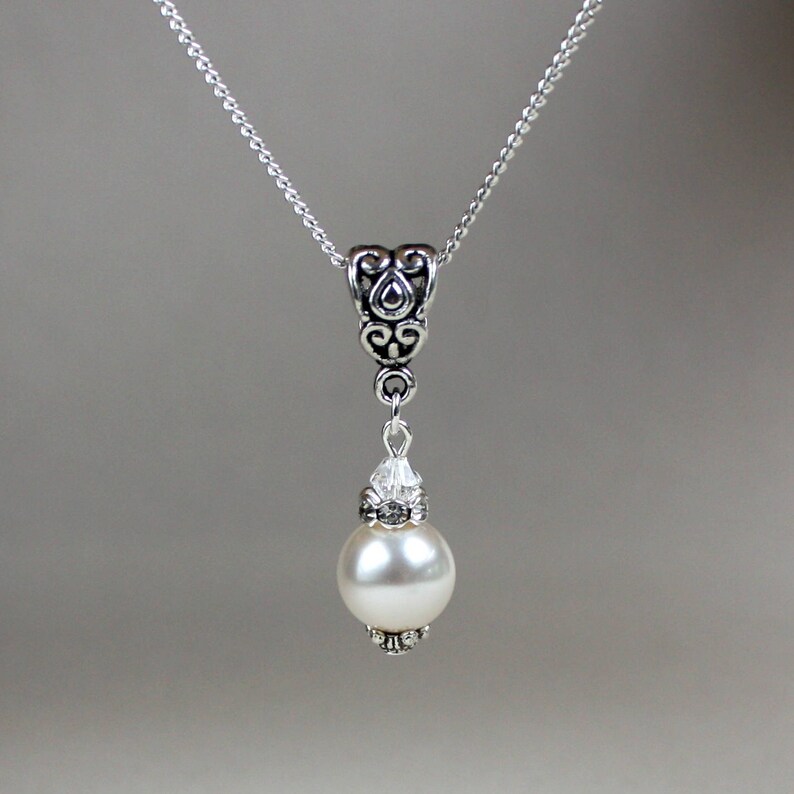 Peut inclure: Un collier en cha&icirc;ne argent avec un pendentif argent&eacute; orn&eacute; d'une perle blanche et d'accents en cristal.