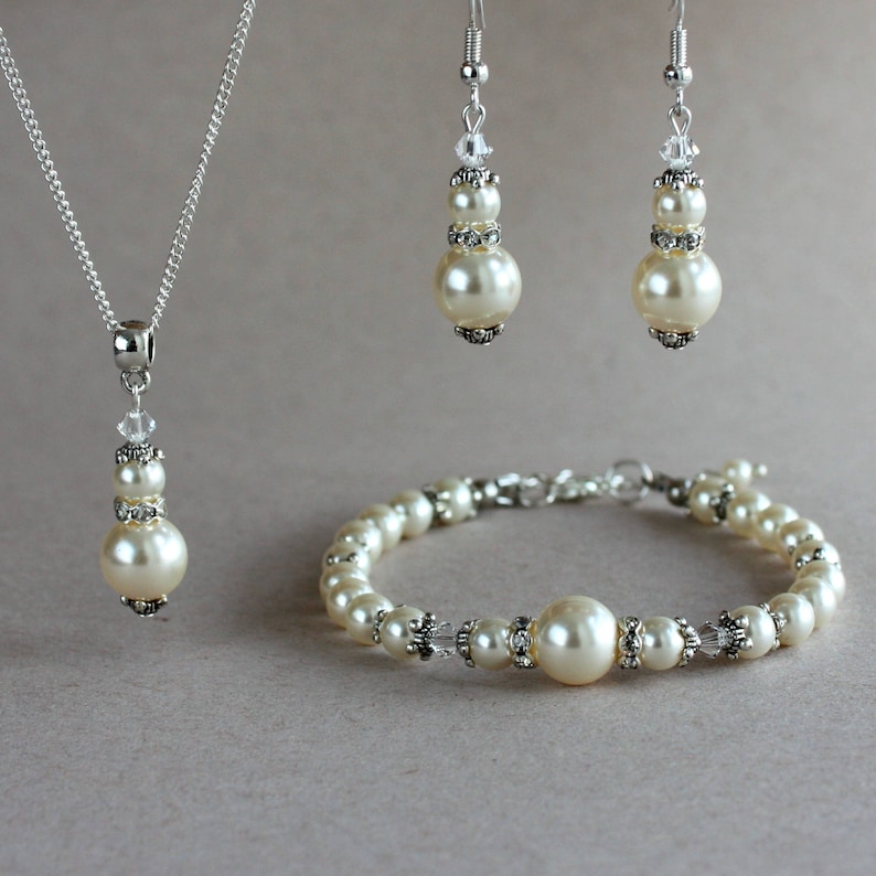 May include: A pearl jewellery set with a necklace, bracelet and earrings. The set features ivory-coloured pearls and clear crystal accents.