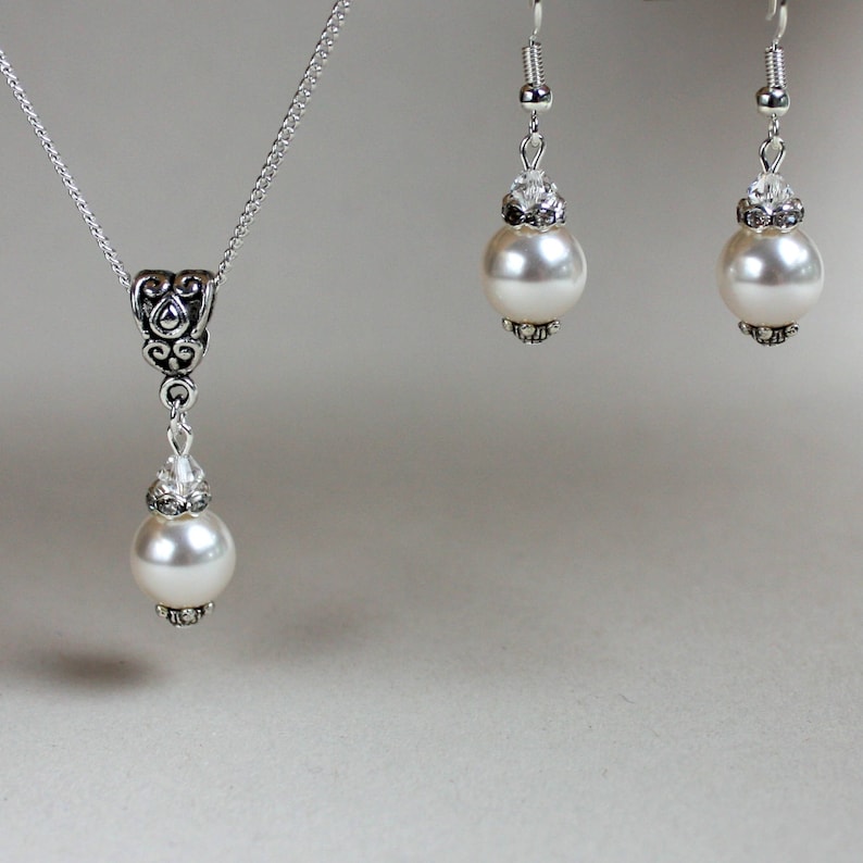 Peut inclure: Un collier et des boucles d'oreilles en argent avec un pendentif en perle et cristal et des boucles d'oreilles assorties en perle et cristal.