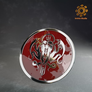 May include: A round, red shield with a silver trim and a detailed silver emblem. The emblem features a trident, stylized wings, and ornate scrollwork. The shield has a glossy finish and is set against a dark background.