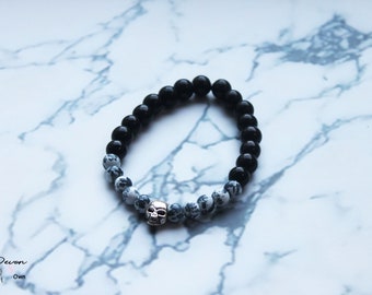 May include: Black and white beaded bracelet with a silver skull charm. The bracelet is made with black onyx and white dalmatian jasper beads.