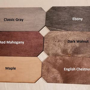 Puede incluir: Seis muestras de madera en diferentes colores y vetas. Las muestras est&aacute;n etiquetadas como "Gris Cl&aacute;sico", "&Eacute;bano", "Caoba Roja", "Nogal Oscuro", "Arce" y "Casta&ntilde;o Ingl&eacute;s".