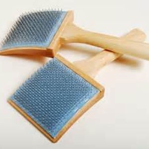 May include: Two wooden handled brushes with blue bristles. The brushes are used for carding wool.