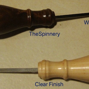May include: Two wooden crochet hooks with different finishes. The top hook has a walnut finish and the bottom hook has a clear finish. Both hooks have a loop at the end for threading yarn.