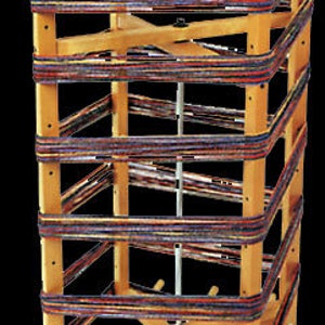 May include: A wooden loom with multiple colorful threads wrapped around it. The loom has a rotating base and a vertical frame with multiple levels.