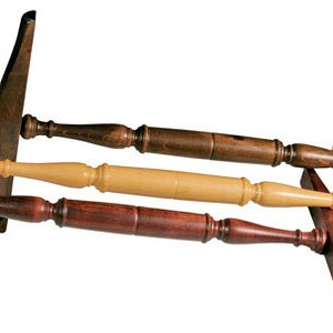 May include: Four wooden tools with curved handles and flat, rectangular blades. The tools are made of different types of wood, including dark brown, light brown, and natural wood. The tools are arranged in a pile, with the handles pointing in different directions.