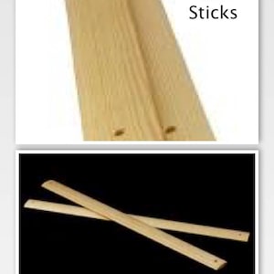 May include: Two wooden sticks, called "Lease Sticks", are shown in the image. The sticks are light brown and have a smooth surface. The sticks are crossed over each other, with one stick on top of the other.