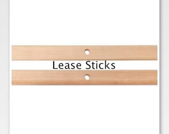 May include: Two wooden sticks with holes in the center. The sticks are light brown and have the text "Lease Sticks" printed on the bottom stick.