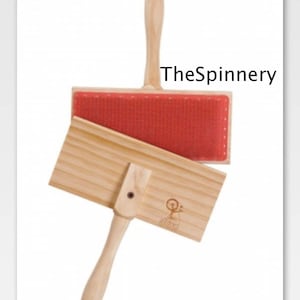 May include: A wooden wool carding tool with a red wool carding surface. The tool is labeled "The Spinnery" and "72 TPI & 108 TPI".