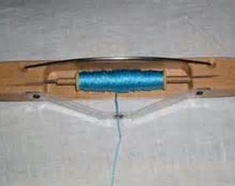 May include: A wooden thread winder with a blue thread spool. The winder has a metal blade and a clear plastic base.