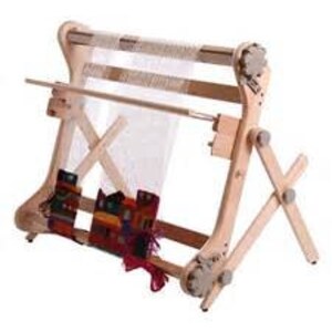 May include: A wooden loom with a natural finish, featuring a warp thread and a woven tapestry hanging from the bottom. The loom has a stand with a cross-shaped support.
