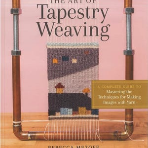 May include: A book titled "The Art of Tapestry Weaving" with a colorful woven tapestry image. The book cover features text and a complete guide to mastering techniques for making images with yarn. The author is Rebecca Mezoff.