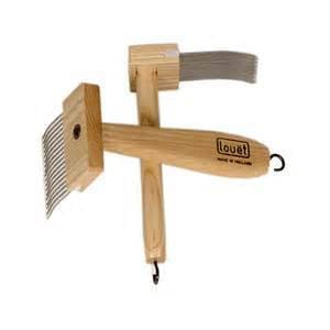 May include: Wooden hand carder with a metal comb and a hook on the end of the handle. The handle is labeled "Louët".