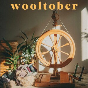 May include: A wooden spinning wheel with a large, round wheel and a smaller, round wheel on the side. The spinning wheel is on a wooden base and is surrounded by yarn and other crafting supplies. The text "Kromski & Sons Wooltober" is visible at the top of the image.
