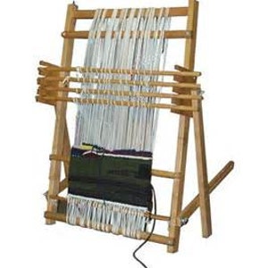 May include: A wooden loom with a white warp and a dark green woven fabric on the bottom. The loom is set up on a wooden stand with a slanted back.