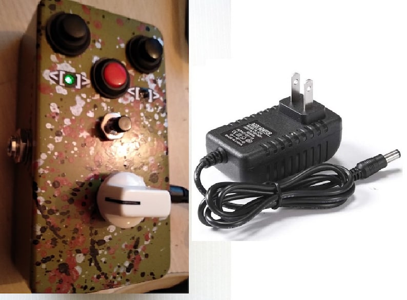 May include: A green and white splatter-painted guitar effects pedal with three knobs, a red button, and a white toggle switch. The pedal is connected to a black power adapter with a US plug.