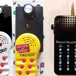 May include: Three handheld sound devices. Two are white and yellow plastic units with red buttons, labelled Reservoir Dogs and Only Fools and Horses In Your Pocket. The third is a black rectangular sound machine with icons and a metallic top spike.