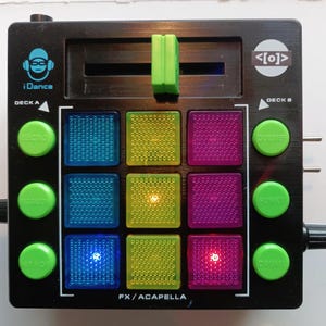 May include: A black iDance DJ controller featuring a grid of nine square, translucent, textured buttons in blue, yellow, and purple, with six round green buttons labelled Electro, Dubstep, Terradon, Funky, Hip Hop, and Drums, and a green slider.